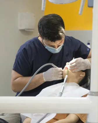 Dentista con mascarilla realizando una exploración a una paciente
