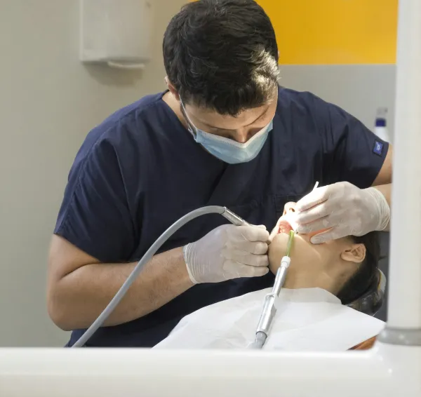 Dentista con mascarilla realizando una exploración a una paciente